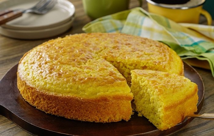Pan de elote estilo guatemalteco recién horneado con una porción separada, un exquisito postre de Guatemala a base de maiz y leche condensada.