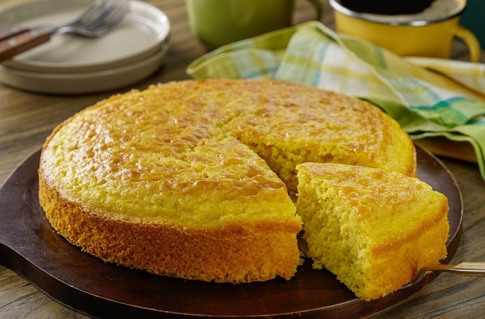 Pan de elote estilo guatemalteco recién horneado con una porción separada, un exquisito postre de Guatemala a base de maiz y leche condensada.