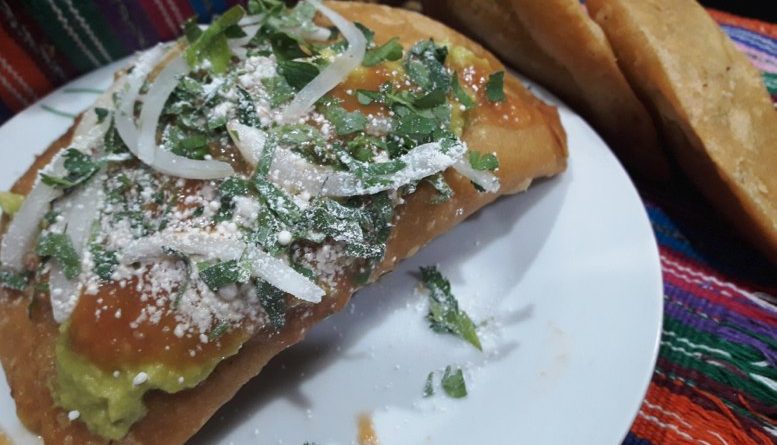 Delicioso platillo de la gastronomía guatemalteca, conocido como dobladas de loroco y queso, sacompañads de salsa roja, cebolla, queso fresco y perejíl