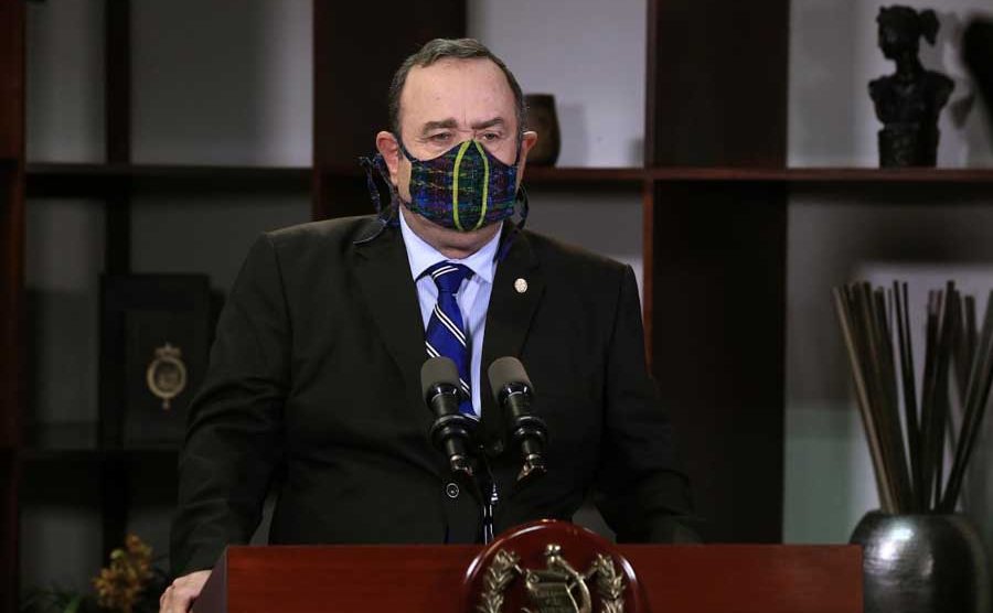 Presidente de Guatemala Alejandro Giammattei, con saco negro y mascarilla negra, dando declaraciones en cadena nacional