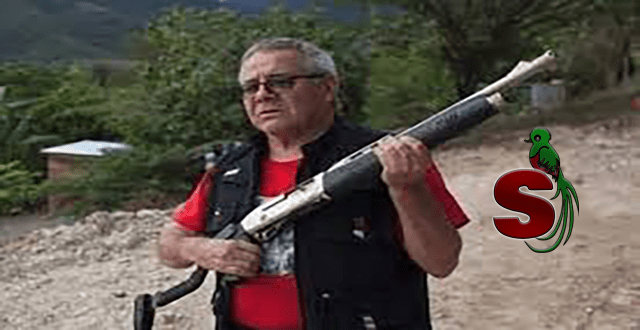 Peligroso terrorista guatemalteco Cesar Montes sosteniendo una escopeta con una playera roja