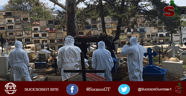 Personas en un cementerio con trajes especiales enterrado a un fallecido por COVID-19